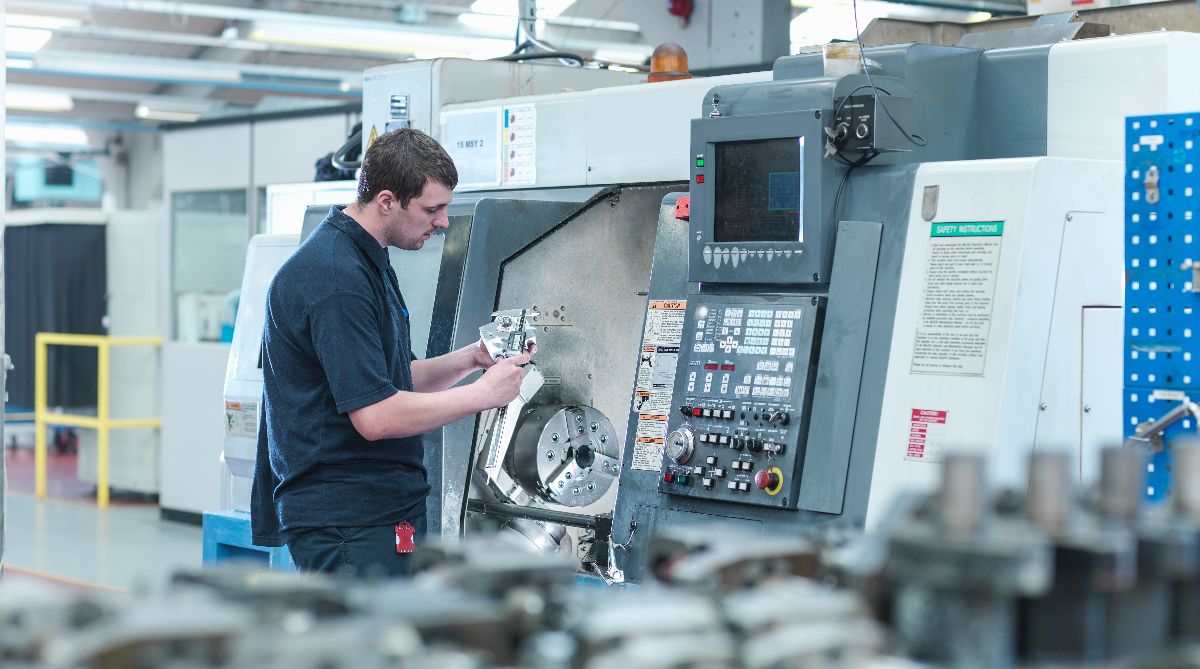 Titan Machining LLC machinist inspecting precision parts on a CNC lathe